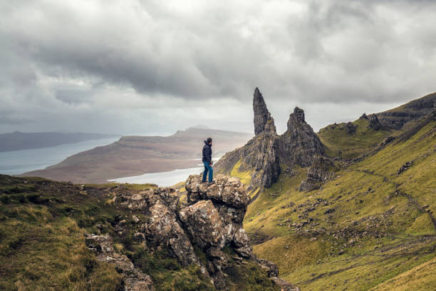 Tourist in Scotland Man overlooking view Old Man of Storr in Autumn on the Isle of Skye, Scotland, UK. isle of skye stock pictures, royalty-free photos & images