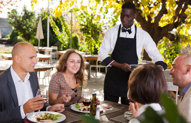 istock Waiter serving meals to friendly company at open-air restaurant 1091309366
