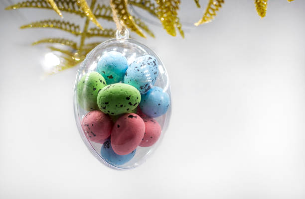 istock Multi-colored Easter eggs hang in a glass transparent egg bauble on white background. 1091324258