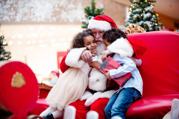 Shopping Christmas with family and Santa Claus at Shopping Mall Multi-Ethnic family shops at Shopping Mall during Christmas Time with Santa Claus. Santa Claus is asking the children what they want for Christmas. Brother and sister happy to see Santa Claus. They are hugging. Santa has arms around children. Boy has gift in his hands. Photo was taken in Quebec Canada. child photos stock pictures, royalty-free photos & images