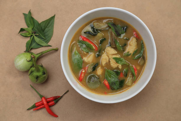 istock Top view of Thai chicken green curry with herbs, basil, small eggplant and red chilli on background. 1091336662