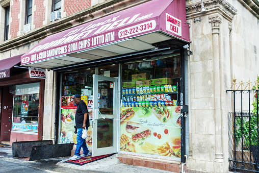 New York City, USA - July 25, 2018: Black man leaving of a grocery in Malcolm X Boulevard, Harlem, Manhattan, New York City, USA