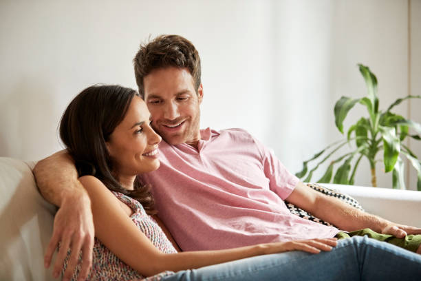istock Smiling man looking at woman while sitting on sofa 1091346316