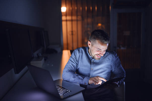 istock Employe smiling and using tablet while sitting in the office late at night. On the desk laptop. 1091347002