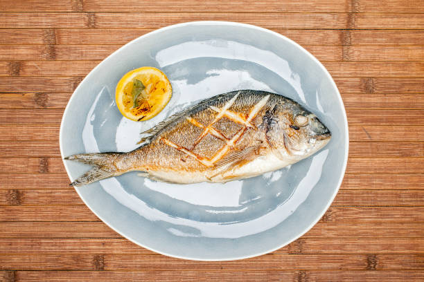 istock Baked fish on a plate with lemon 1091347484