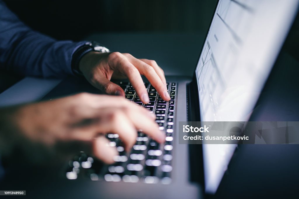 Close up of hands typing on laptop. Night work concept. Laptop Stock Photo