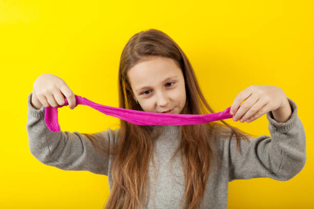 istock Education experiments in elementary school. Kid girl play with slime on yellow background 1091355346