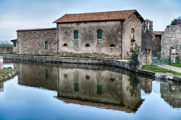 Perussin, France - April 24, 2018: Chateau de Virieu is an old stone chateau with strong reflections from a small pond in the town of Perussin in France.