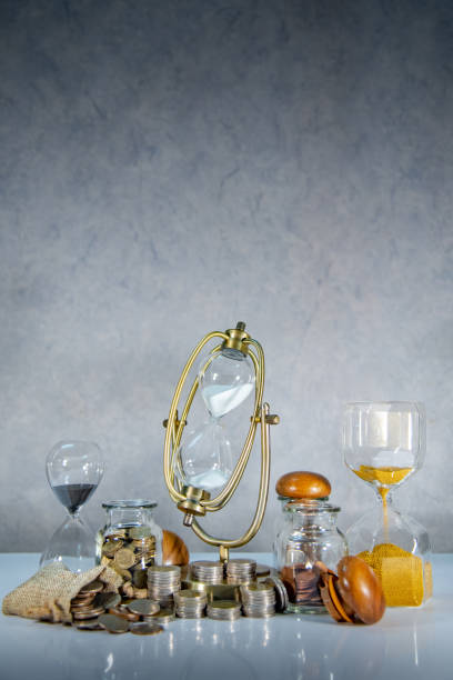 istock Sand running through the shape of hourglass with coins stack and currency jars on table. Time investment. Retirement saving concept. Urgency countdown timer for business payment deadline 1091374436