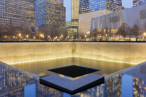 New York City, USA - February 1, 2018: Night time view of Manhattan skyscrapers and the reflecting pools of National September 11 Memorial commemorating the 9/11 attacks and the 1993 World Trade Center bombing. It is located at ground zero where the former World Trade Center twin towers originally stood.