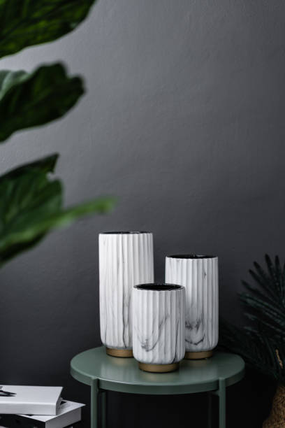 istock Isolated composition of white marble ceramic vase on green metal side table in artificial plants and stack books scene on gray painted wall background / object isolation / interior design scene 1091380348