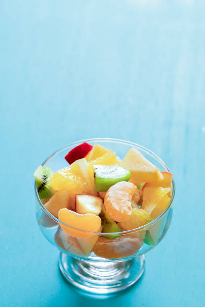 istock Fresh fruit salad in glass bowl on turquoise background with copy space. 1091382454