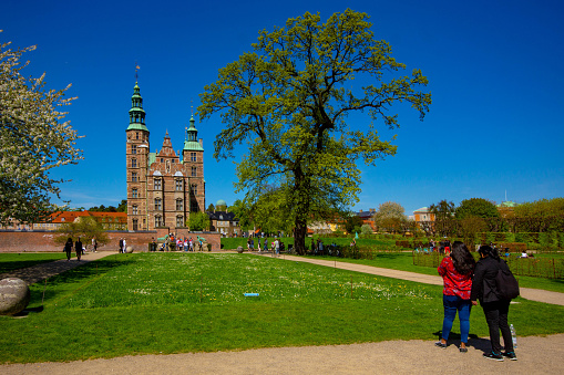 Rosenborg Castle in central Copenhagen, Denmark, was built and extended between 1606 and 1633 in Dutch renaissance style by King Christian IV. This is in front of the castle with tourists taking photos across the castle grounds.