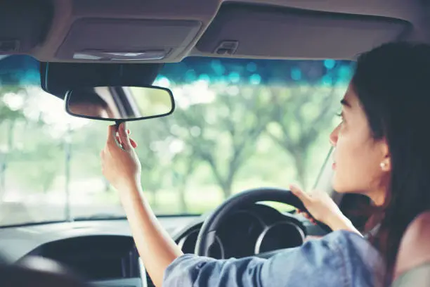 Photo of Asian women are adjusting the rearview mirror of the car