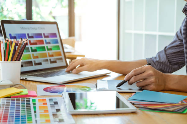 Young creative graphic designer working on project architectural drawing and color swatches, selection coloring on graphic chart with work tools and equipment