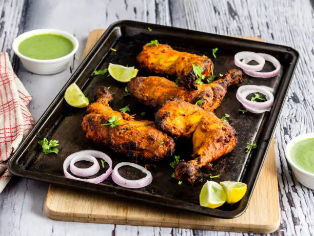 Indian Style Chicken Leg Kebabs on a Roasting Tray with Cilantro and Onion