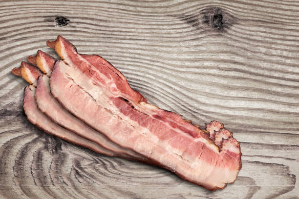 istock Three Pork Bacon Rashers Set On Old Knotted Weathered Cracked Pinewood Picnic Table Rustic Rough Grunge Surface 1091391690