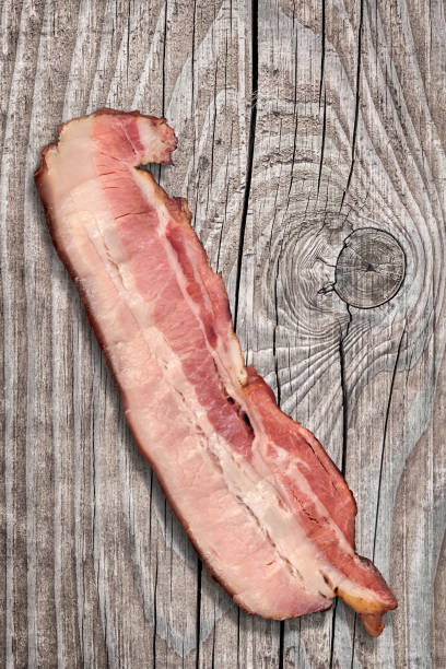 istock Single Pork Bacon Rasher On Old Knotted Weathered Cracked Pinewood Picnic Table Rustic Rough Grunge Surface 1091391692