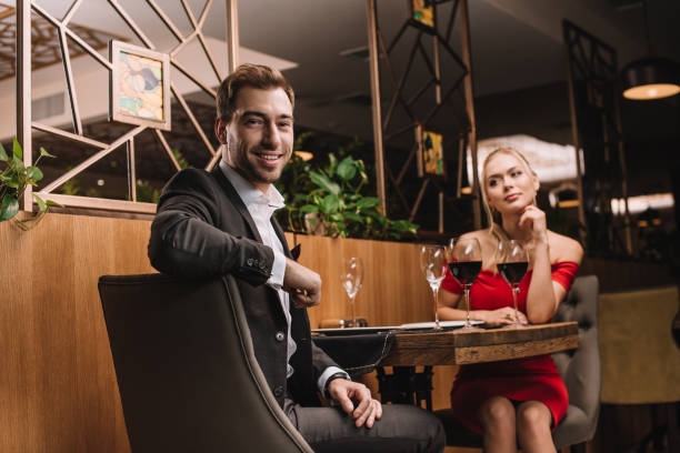 istock handsome man looking at camera and smiling while sitting in restaurant with girlfriend 1091397812