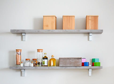 Arranged jars and wooden boxes  with various spices on kitchen shelves. Selective focus of arranged jars with various spices on kitchen shelves