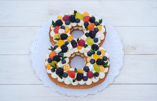 beautiful homemade cake in the shape of number eight with natural berries on white background. cake for international women's day, birthday cake.