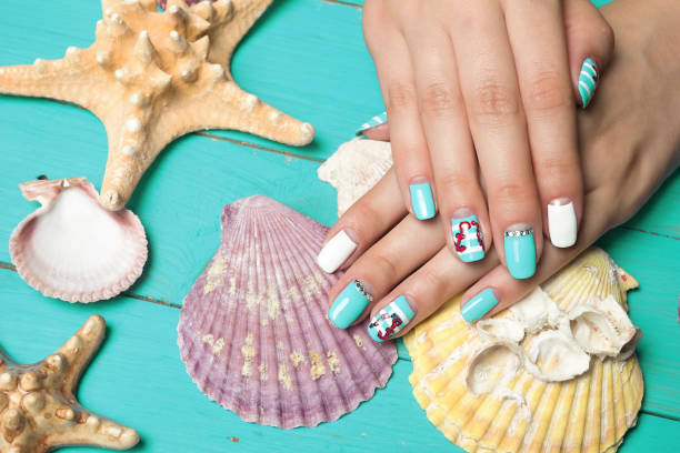 French manicure - beautiful manicured female hands with marine manicure with rhinestones on background seashells and starfish stock photo