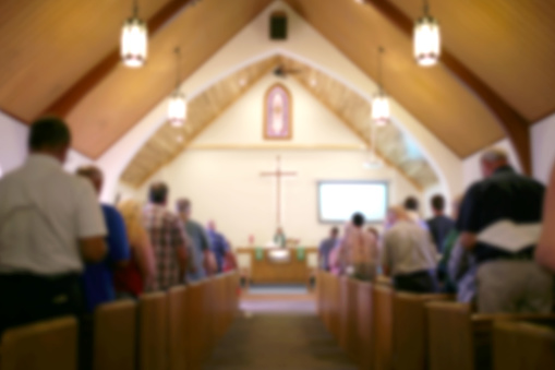 Foto borrosa del Iterior de un santuario de la iglesia con la congregación, el Pastor y una gran cruz Visible photo