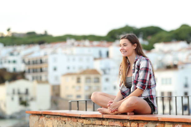istock Happy teen contemplating views sitting on a ledge 1091406596
