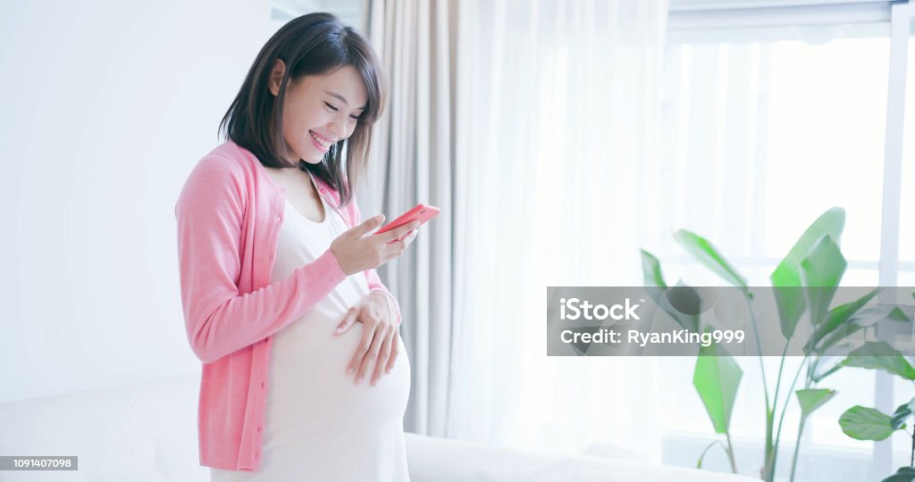 pregnant woman use smart phone pregnant woman use smart phone at home Pregnant Stock Photo