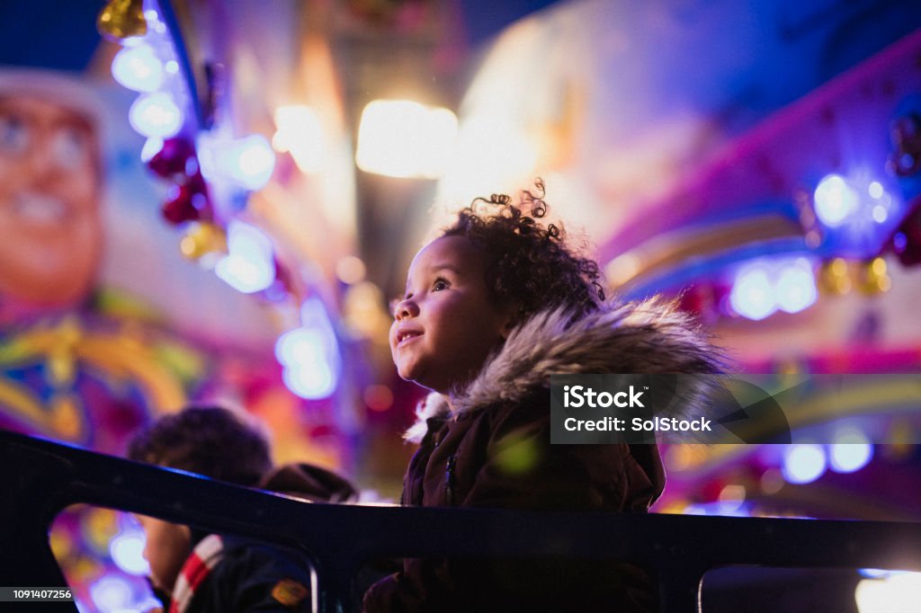 First Time at the Funfair A close-up shot of a little girl's first time at the funfair​, she is looking at all of the decorations in awe. Amusement Park Stock Photo