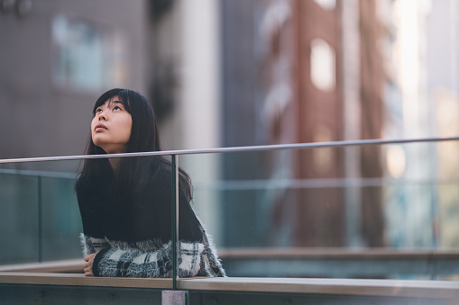 A portrait of a young calm Asian woman while she is daydreaming.