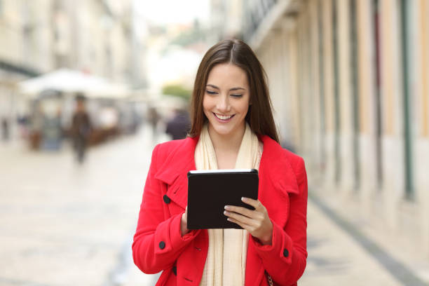 Happy woman checking tablet content in the street