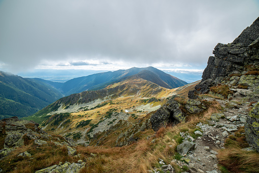 rocky Tatra mountain tourist hiking trails under blue sky and occasional mist  cloud in Slovakia, path to Volovec mountain