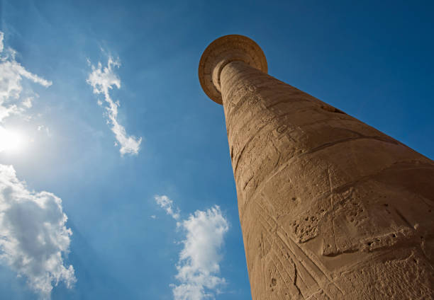 Columns with hieroglyphic carvings in hypostyle hall at anciant egyptian Karnak Temple in Luxor against blue sky background