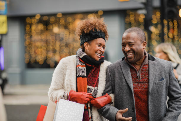 Quality Time Together at Christmas Senior couple crossing the road on a city street. They are walking with shopping bags while Christmas shopping. winter city stock pictures, royalty-free photos & images