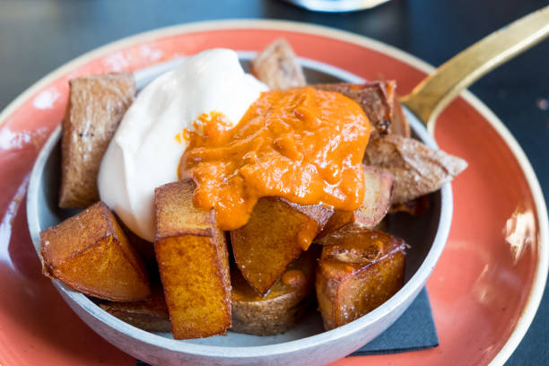 close up of inviting bowl of traditional spanish "patatas bravas", appetizer made with potatoes and paprika and garlic sauce stock photo