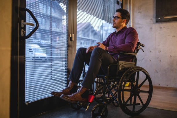 istock Grumpy man in a wheelchair looking through his office window 1091441644