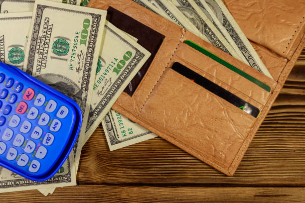 istock Opened wallet, calculator and american dollars banknotes on wooden table. Top view 1091446474