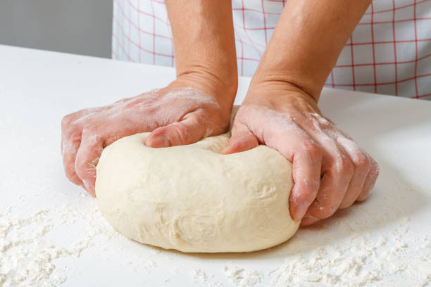 istock Woman kneads raw fresh dough with hands on the table 1091446874