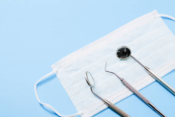 歯科器械: 2 つのミラーと歯科用探針の光医療マスクで、左が横になっている青い背景。 - dentist mirror orthodontist carver ストックフォトと画像