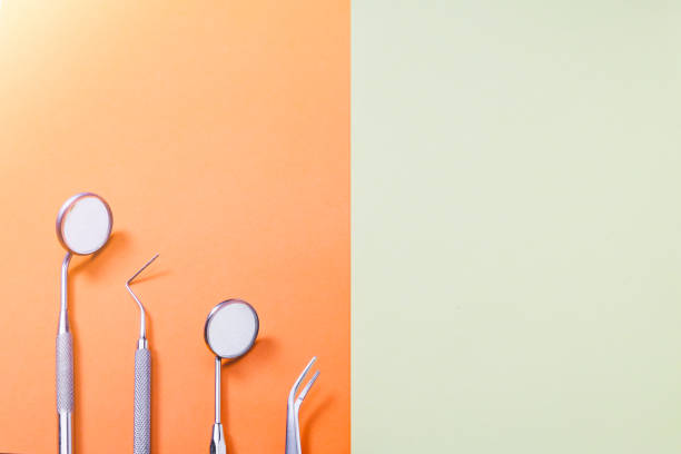 istock Dentist useful tools: two mirrors, explorer and tweezers on orange yellow bacrground with copy space. 1091448782