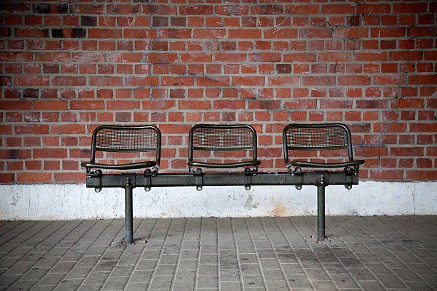 bench with three seats in front of a brick wall