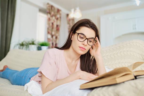 istock A girl in glasses lying on the sofa reading a book. 1091456180