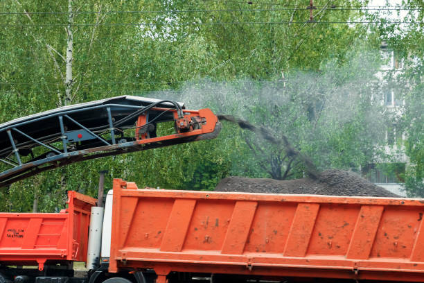 istock The machine is cutting asphalt, cutting old asphalt with a special machine and loading it into a dumper on a summer day. Repair of roads, replacement of asvalt, construction work. 1091465434