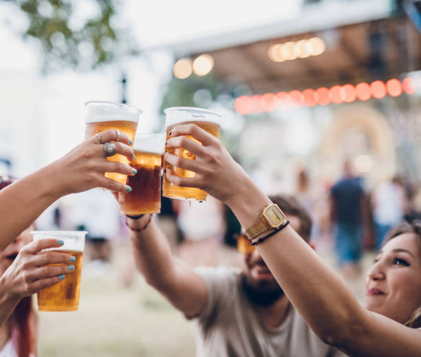 Group of people on a music festival Group of four friends toasting with beer on a music festival disposable cup stock pictures, royalty-free photos & images