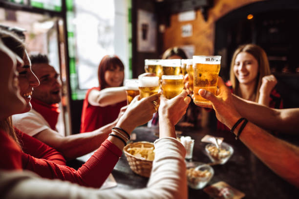 la gente habla y tostar en un pub con las cervezas - bebida alcohólica fotografías e imágenes de stock