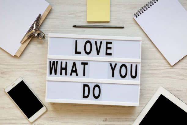 istock Modern board with text 'Love what you do', tablet, smartphone, notepad and pencil over white wooden background, top view. Business concept. From above, flat-lay, overhead. 1091469604