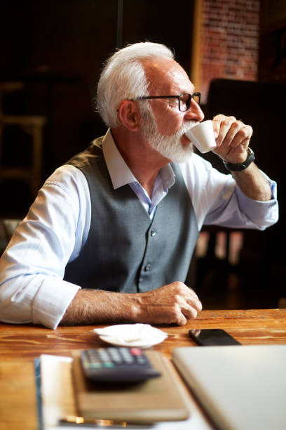 istock Elderly manager drinking coffee in a cafeteria while taking a break from working on the go 1091471828