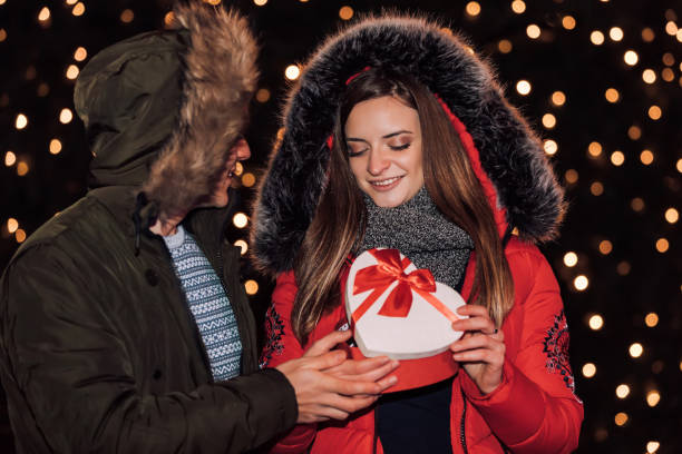 istock Young couple together opens box with a gift at winter evening 1091482684