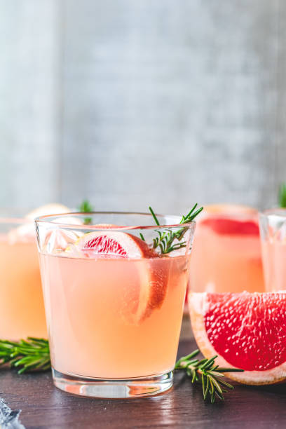 Fresh pink alcoholic cocktail with grapefruit, ice and rosemary
